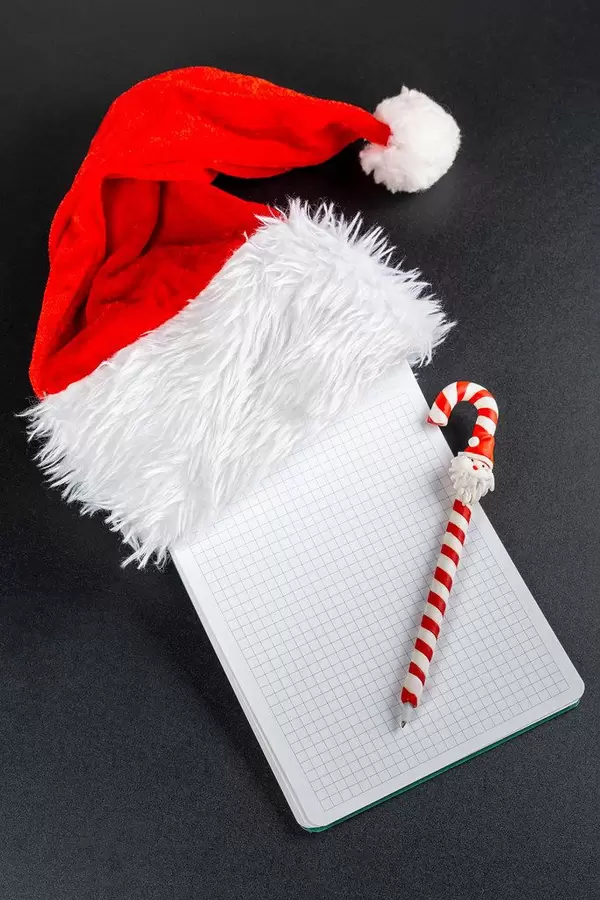 Santa's hat with blank card and pen to write christmas message on black background