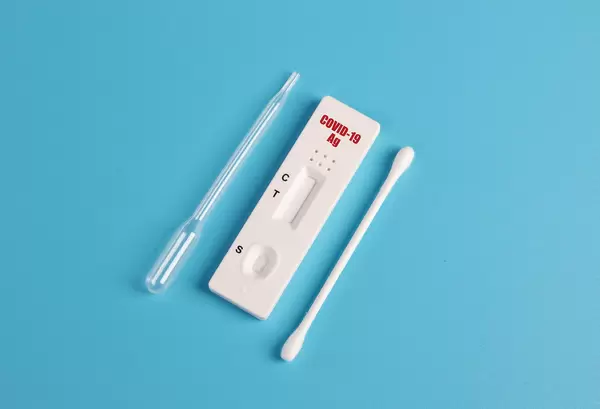 SARS-CoV-2 Rapid Antigen Test isolated on blue background with nasal swab stick