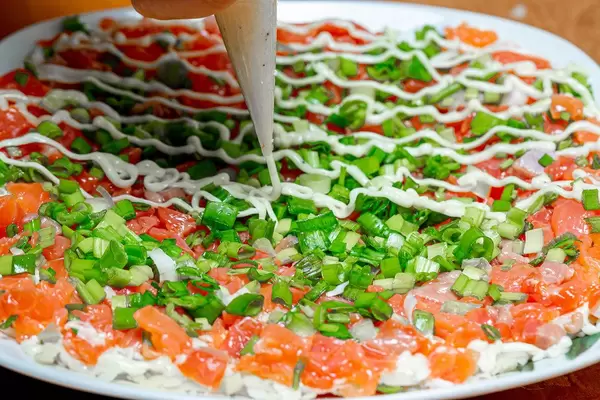 Sauce for salad is squeezed out of a pastry bag