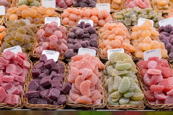 Saure Drops und farbenfrohe spanische Süßigkeiten in Holzkörben am Marktstand im Mercat de la Boqueria, Barcelona