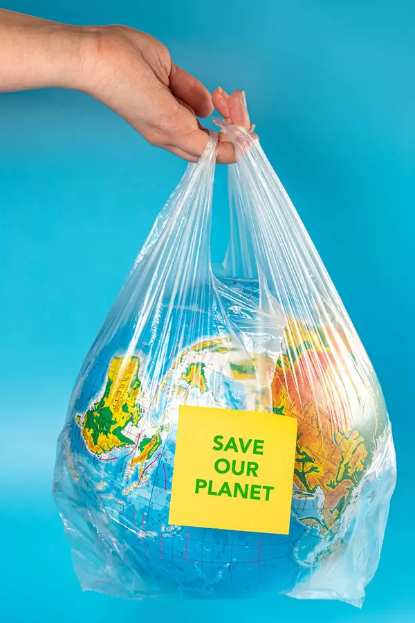 Save our planet inscription on globe in plastic bag