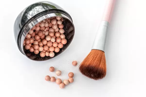 Scattered blush balls on a white background with a brush