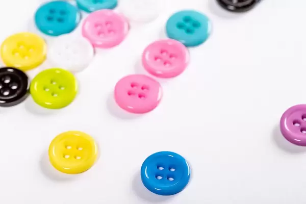 Scattered colored buttons for clothes on a white background (Flip 2019)