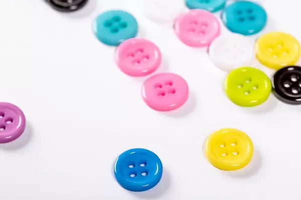 Scattered colored buttons for clothes on a white background
