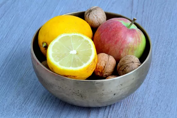 Schale mit Nüssen, Zitrone und Apfel