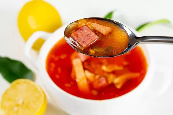 Scharfe Suppe Soljanka, mir geräuchertem Hähnchenfleisch, Kalbfleisch und Schinken auf einem Löffel, in der Nahaufnahme
