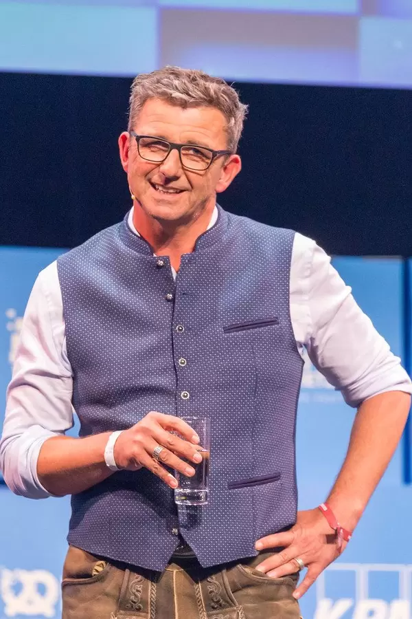 Schauspieler Hans Sigl hält ein Glas in der Hand während seiner Stand-Up Session bei Bits & Pretzels 2019