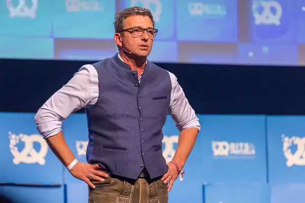 Schauspieler Hans Sigl in Lederhosen auf der Bühne mit den Händen auf den Hüften