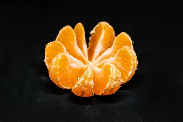 Scheiben einer Mandarine vor schwarzem Hintergrund