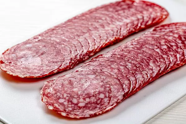Scheiben von geräucherter Salamiwurst, auf weißem Küchenbrettchen