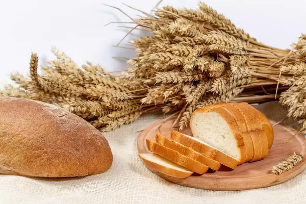 Scheiben Weißbrot und ein Rogenbrot mit Weizenähren auf weißem Hintergrund