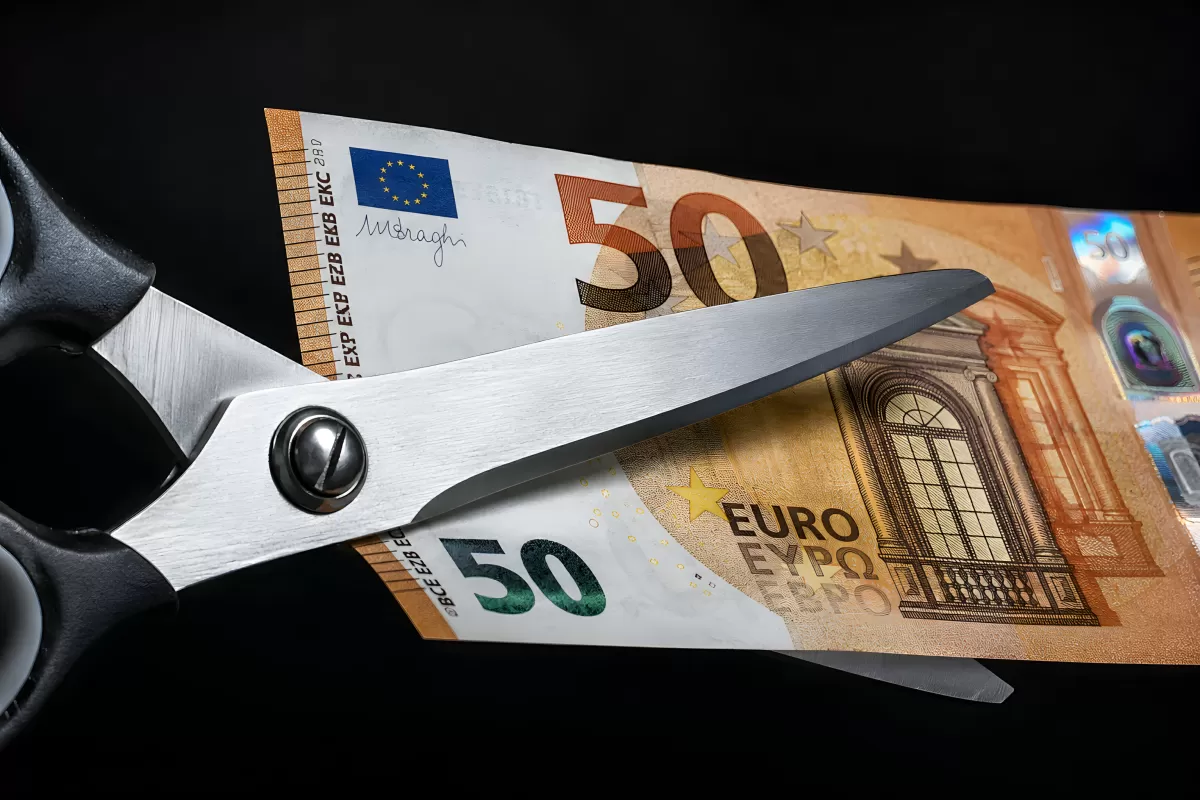 Schere schneidet 50-Euro-Schein auf schwarzem Hintergrund