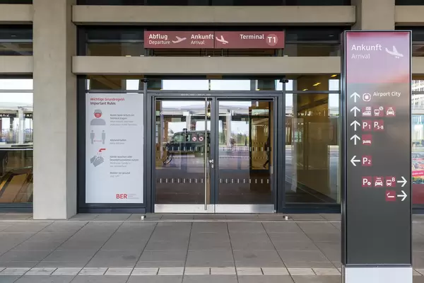 Schild mit Corona-Regeln (Maske, Abstand, Hände-Desinfektion) am Eingang vom Flughafen BER T1
