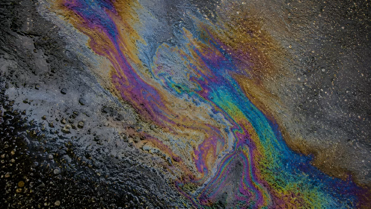 Schillernde Ölschliere auf nassem Asphalt