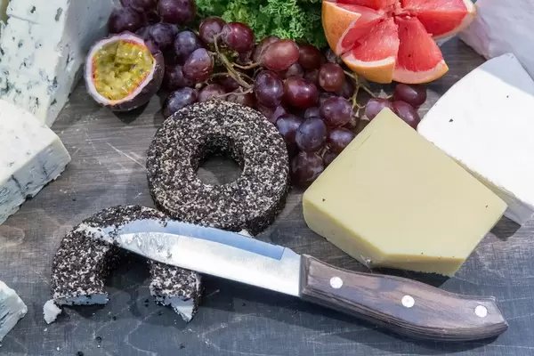 Schimmelkäse, Frischkäse und Hartkäse liegt mit einem Messer auf einer Holzoberfläche neben frischem Obst