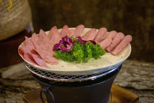 Schinkenwurst Aufschnitt mit Petersilie und Dekoration auf einem Teller bei einem Hotel Frühstücksbuffet Nahaufnahme