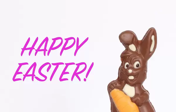Schokoladen-Osterhase neben Text Happy Easter vor weißem Hintergrund