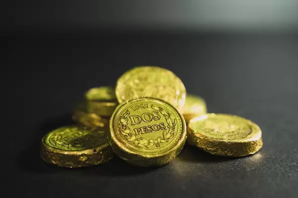 Schokoladenmünzen in goldener Verpackung mit dem spanischen Aufdruck "Dos Pesos", auf schwarzem Untergrund