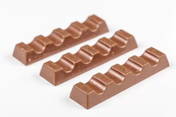 Schokoriegel aus Milchschokolade liegen nebeneinander auf einem weißen Tisch