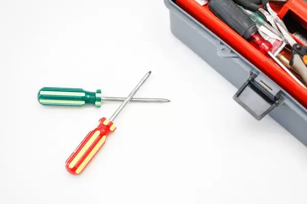 Schraubenzieher und Werkzeugkiste vor weißem Hintergrund