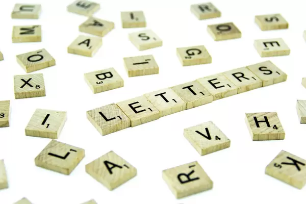 Schriftzug LETTERS auf Holzplättchen zwischen unsortierten Scrabble-Steinen