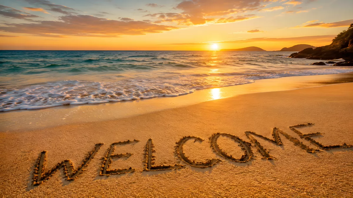Schriftzug Welcome im Sand bei Sonnenuntergang