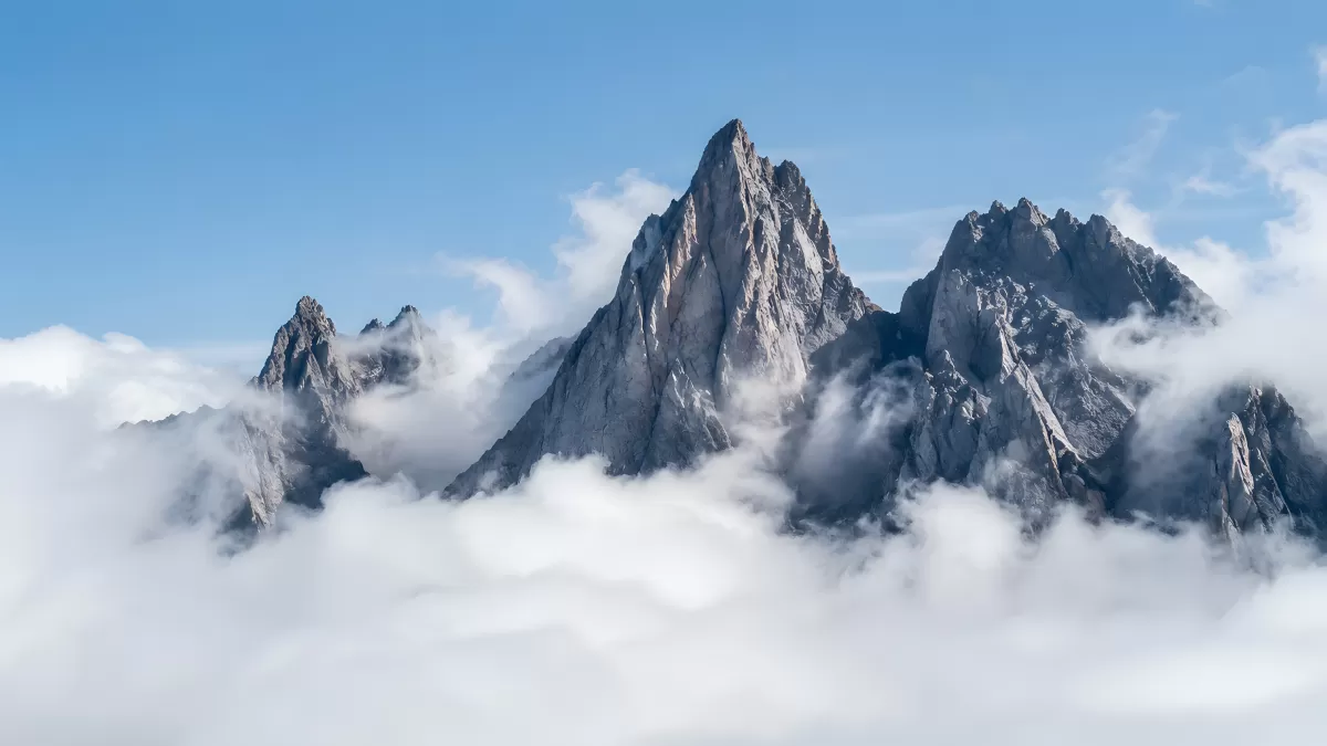 Schroffe Berggipfel ragen durch Wolkendecke in Alpen