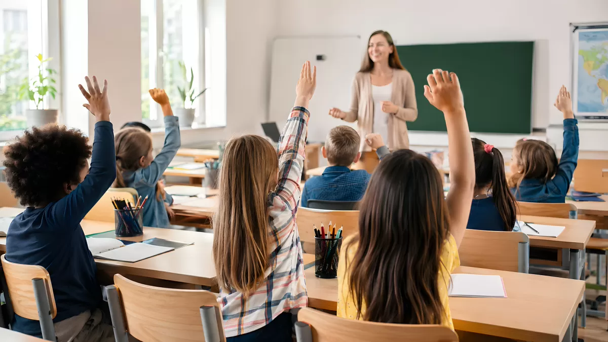 Schüler heben Hände im Grundschulunterricht