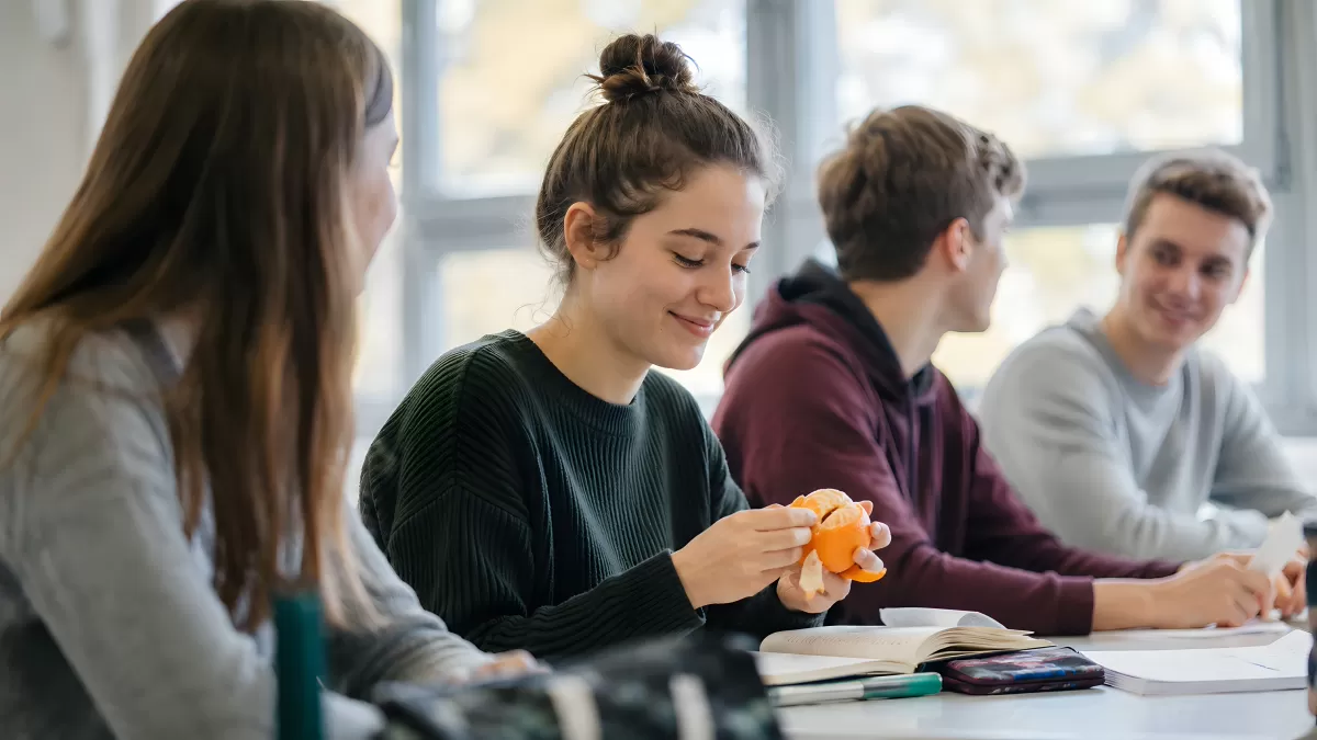 Schüler in der Pause mit Mandarine und Büchern