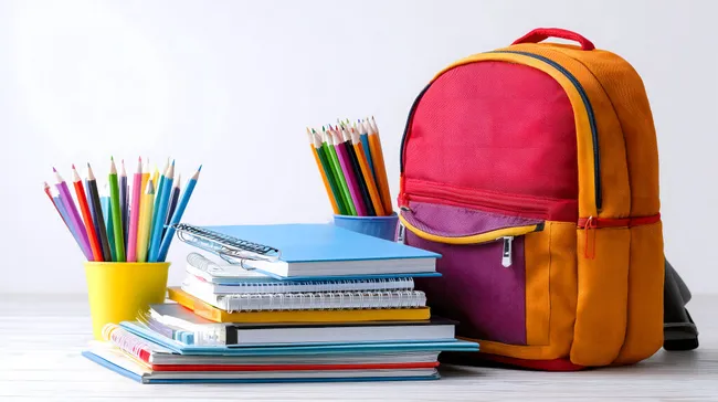 Schulbedarf und Rucksack auf Tisch