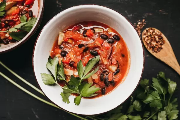 Schüsseln mit Chili aus schwarzen Bohnen, Knoblauch und Tomaten, dekoriert mit Petersilie