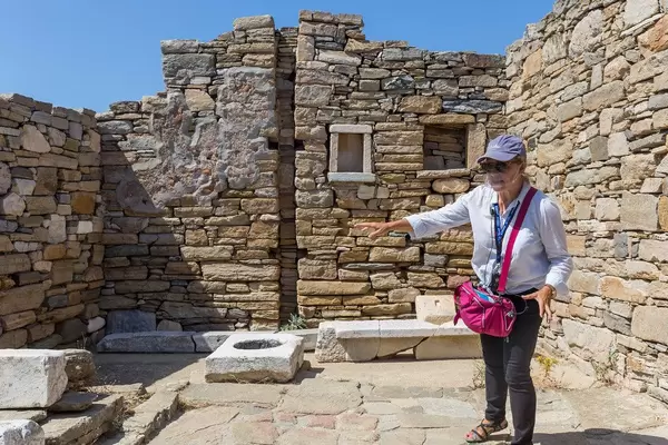 Schutz vor Corona: Reiseleiterin auf Delos trägt transparentes Visier, das Mund und Nase bedeckt