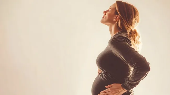 Schwangere Frau mit Rückenschmerzen hält den Bauch