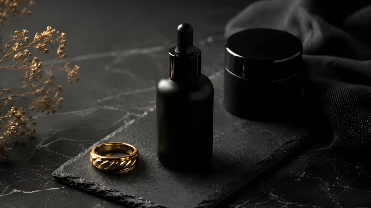 Schwarze Kosmetikflaschen mit goldenem Ring auf Marmor