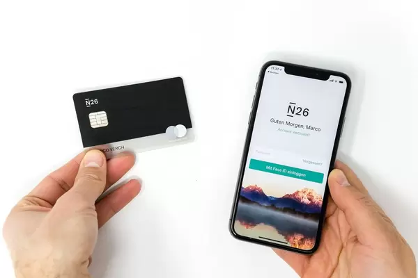 Schwarze N26 Bankkarte mit der Login-Seite des N26 Mobil-Applikations zeigt an einem iPhone