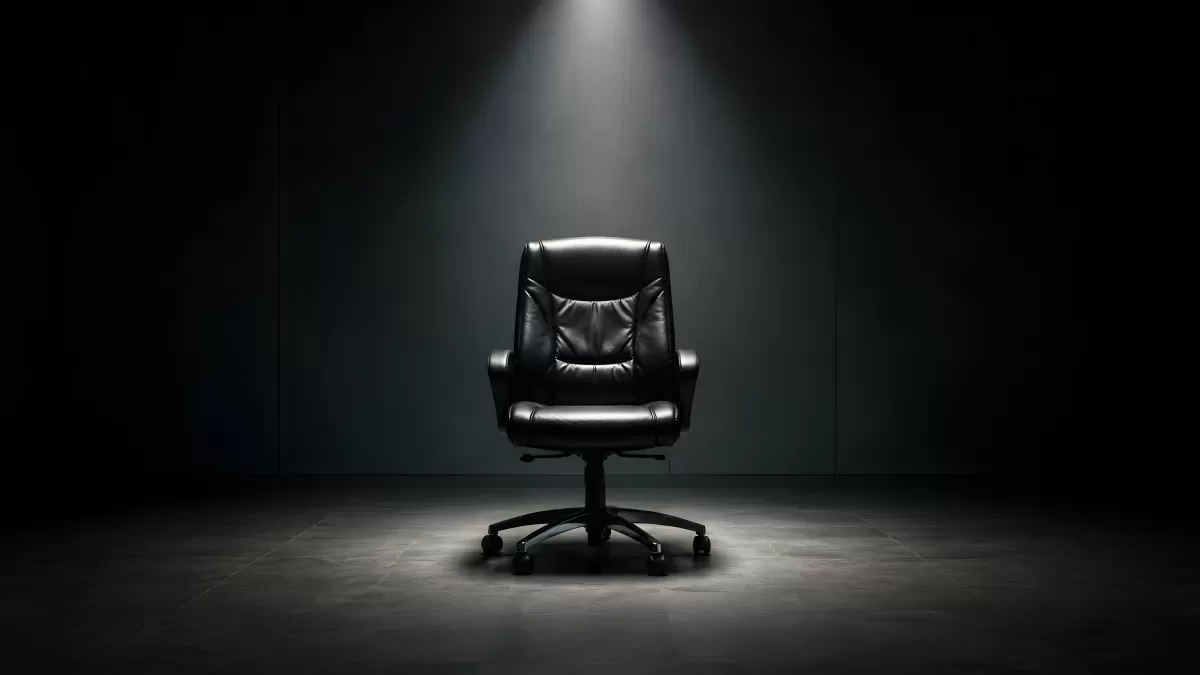 Schwarzer Bürostuhl im Scheinwerferlicht auf dunklem Hintergrund