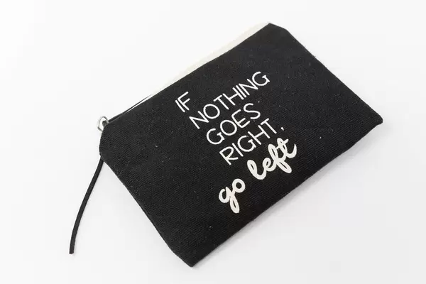 Schwarzer Kulturbeutel mit Schrift "If nothing goes right, go left" in Weiß vor weißem Hintergrund