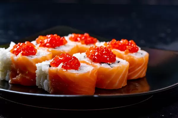 Schwarzer Teller mit sechs Philadelphia Sushi Rollen mit Lachs, Käse und Kaviar-Topping