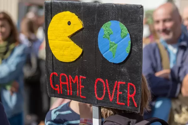 Schwarzes Demonstrationsschild mit Pac-man frisst die Welt Symbolik