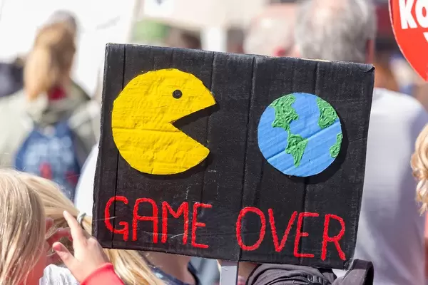 Schwarzes Demonstrationsschild zeigt Pac-man frisst die Welt bildlich mit der Unterschrift "Game Over"
