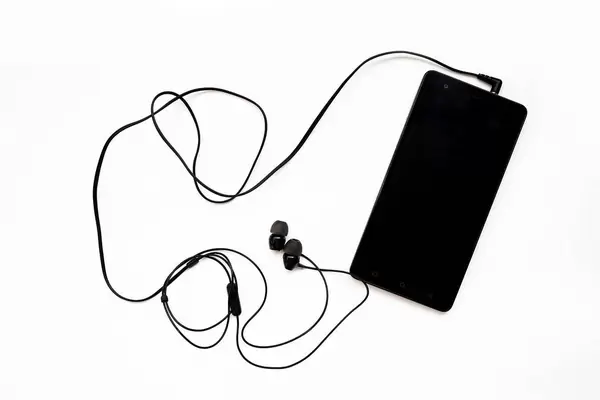 Schwarzes Smartphone mit angeschlossenen In-Ear-Kopfhörern vor weißem Hintergrund