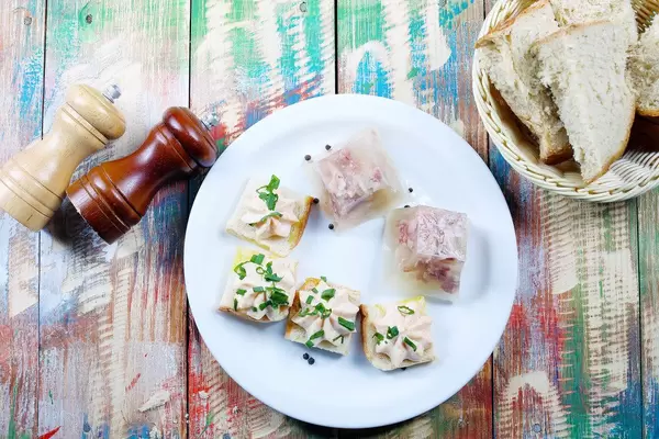 Schweinefleisch in Aspik serviert mit hausgemachtem Weißbrot, Salz und Pfeffer. Hölzerner Hintergrund im Vintage-Stil
