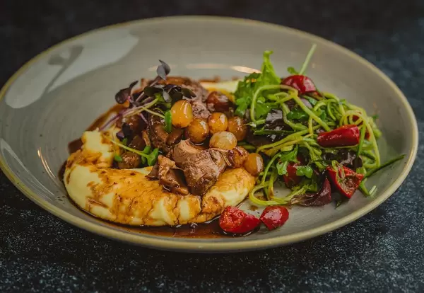 Schweinegeschnetzeltes mit Stachelbeeren, einem frischen Salat und gestampften Kartoffelpüree - frontale Nahaufnahme
