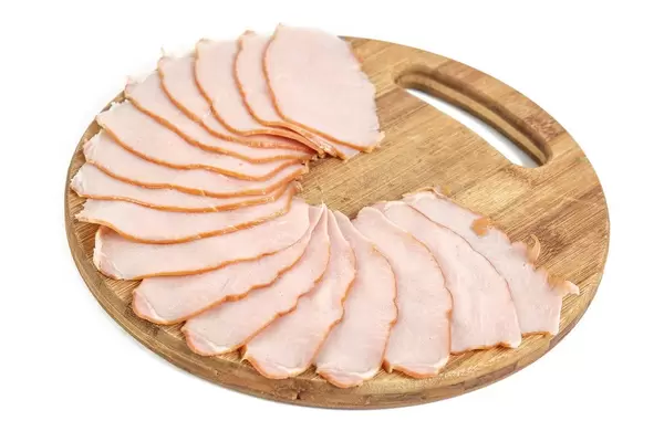 Schweineschinken auf rundem Holzbrett für die Brotzeit arrangiert