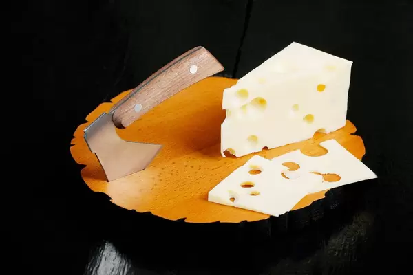 Schweizer Käse mit Löchern, neben einem Hackebeil