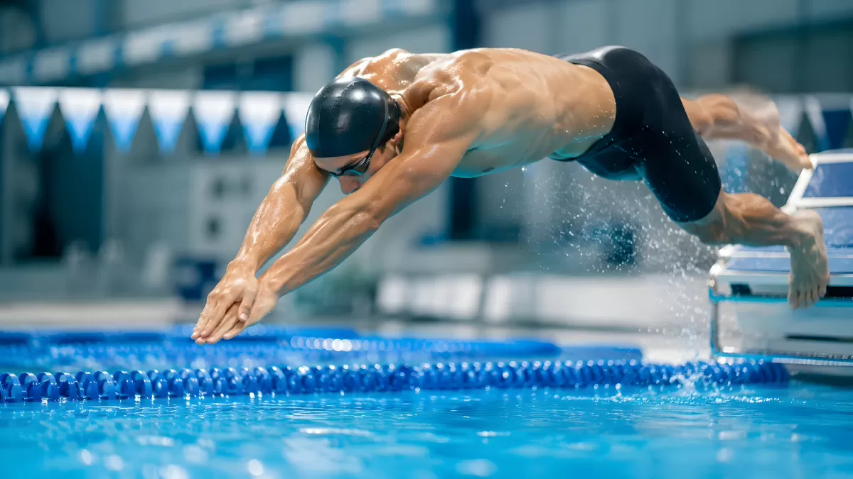 Schwimmer springt vom Startblock ins Wettkampfbecken