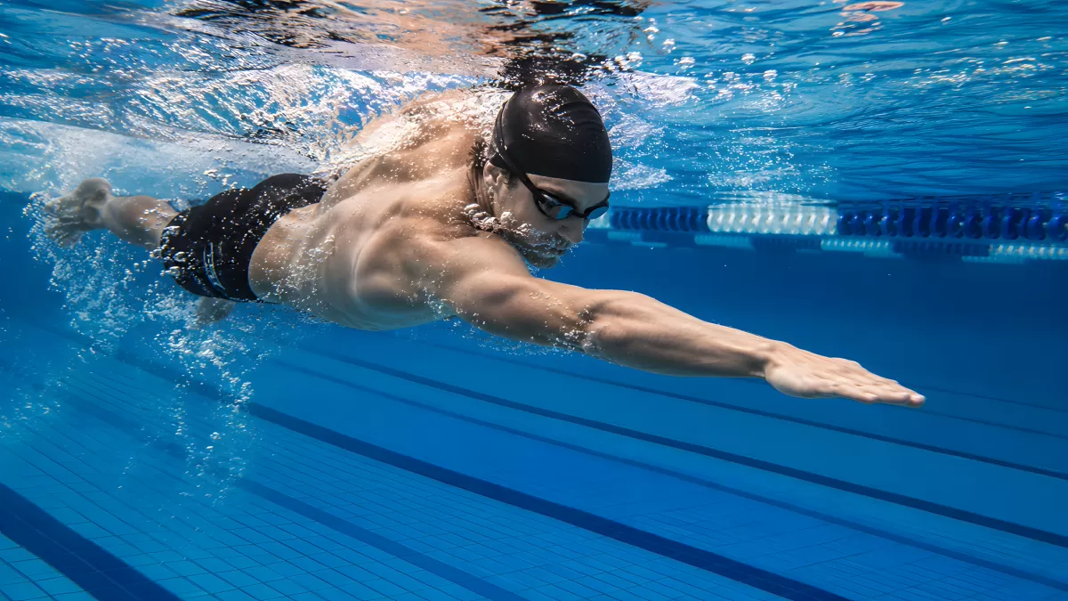 Schwimmer taucht dynamisch durch Hallenbad-Becken