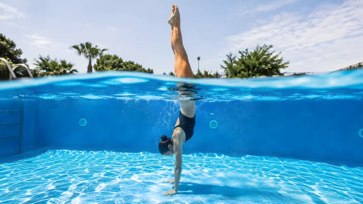 Schwimmerin macht Handstand unter Wasser im Pool