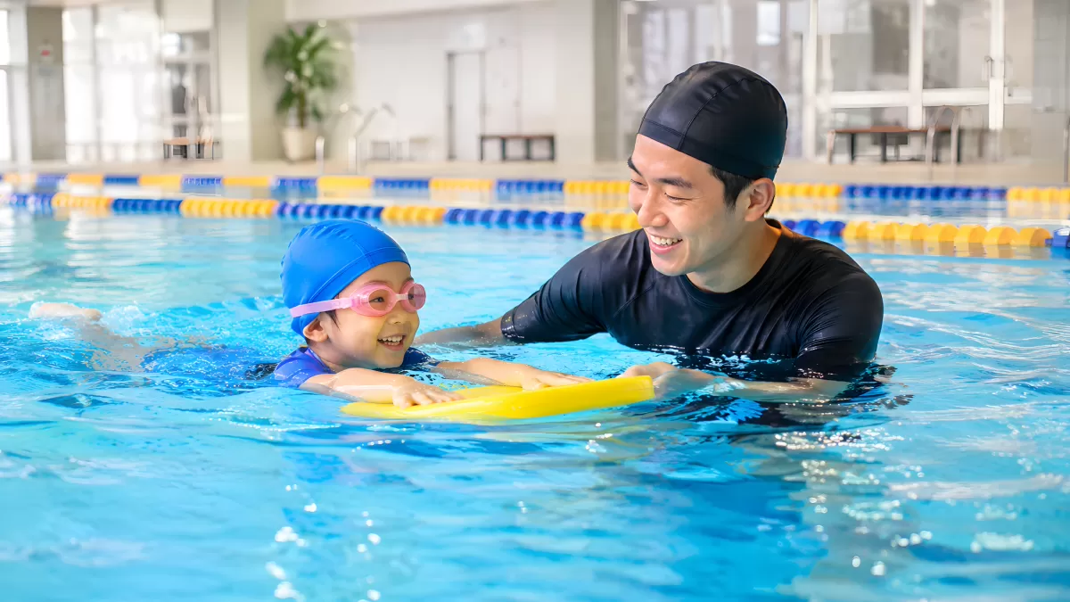 Schwimmlehrer unterrichtet Kind im Hallenbad
