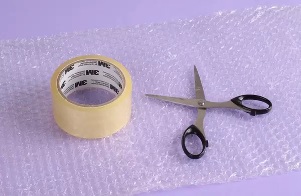 Scissors, duct tape and bubble wrap on a purple table